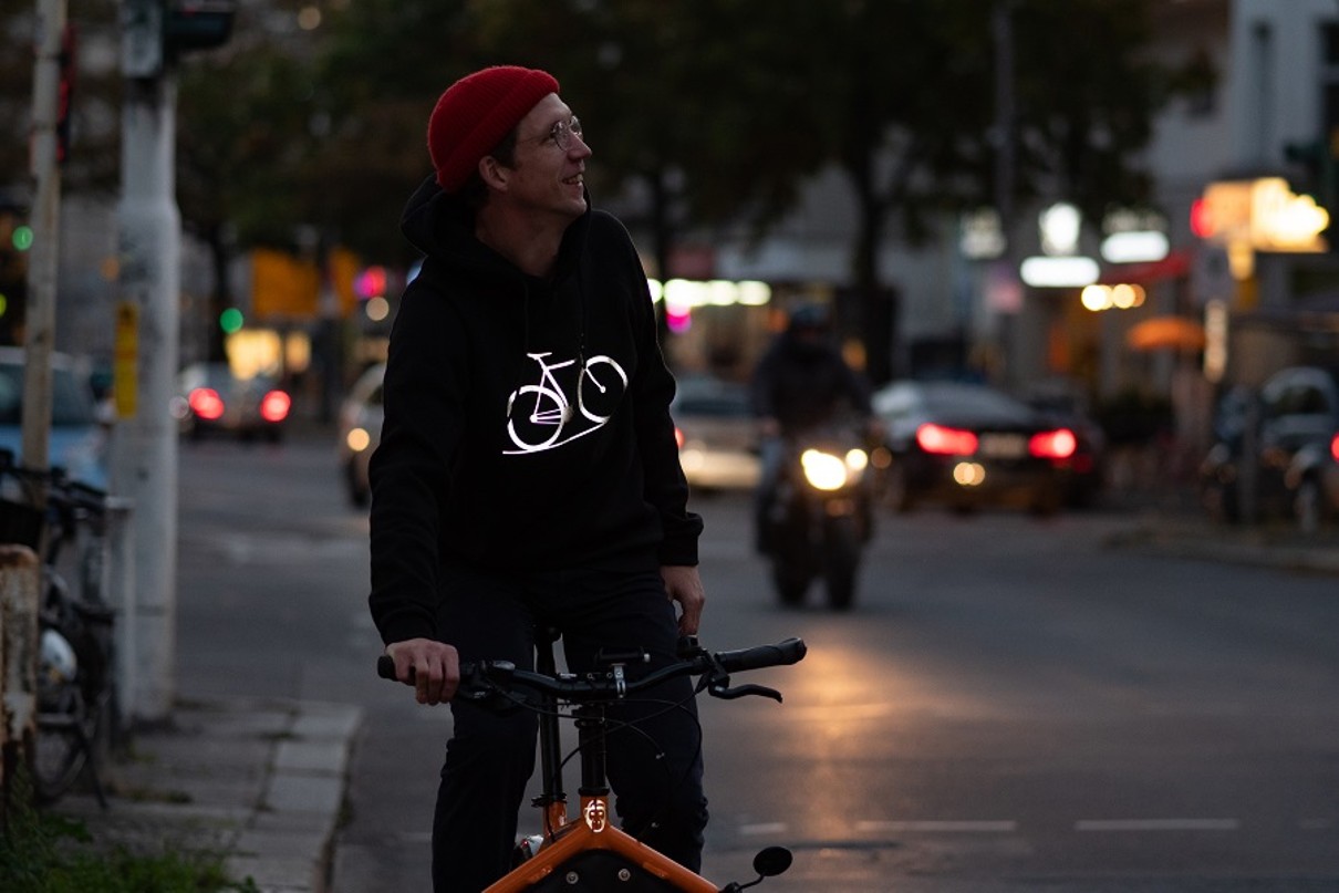 Ein Mann auf einem Fahrrad, er trägt einen reflektierenden Pullover.